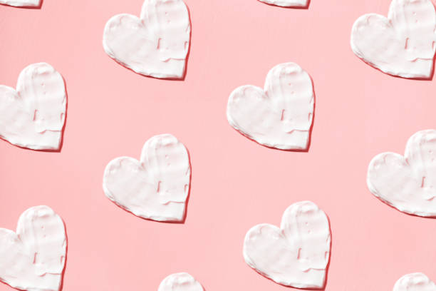 Hearts pattern from cream in pink background. Skin care stock photo