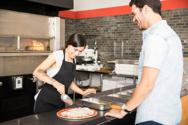 istock Cheerful chef preparing pizza for customer standing at counter 1000837780