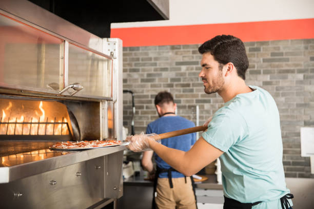 istock Chef cooking pizza and putting it in the oven to bake 1000837990