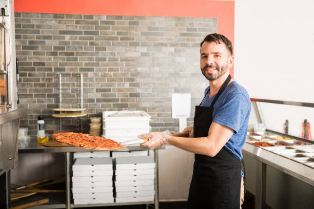 istock Chef with a pizza on a shovel in a kitchen of a restaurant 1000838494
