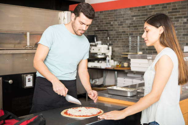 istock Cook in the kitchen putting the ingredients on the pizza 1000838642