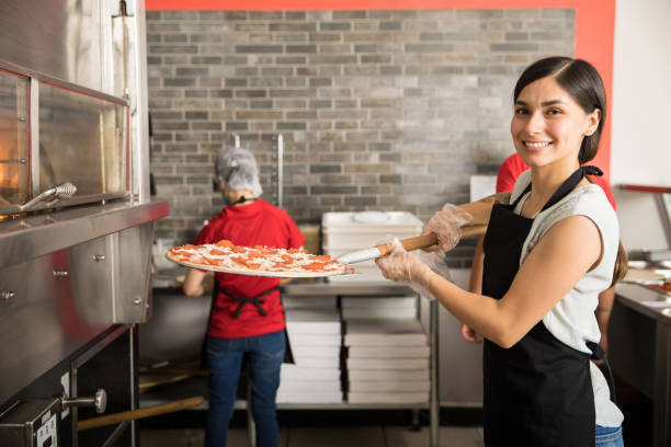 istock Pretty woman chef putting fresh made pizza in oven 1000841944