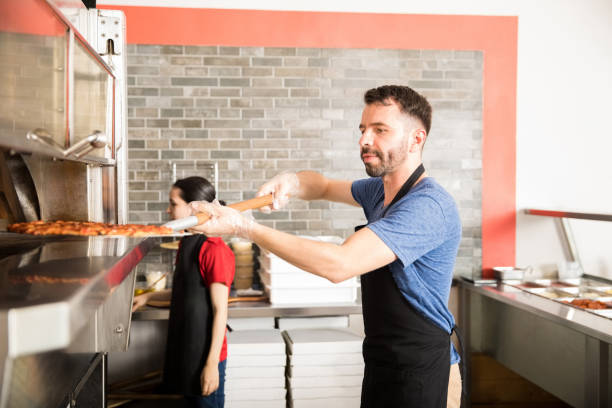 istock Restaurant chef removing freshly baked pizza out of oven 1000842026
