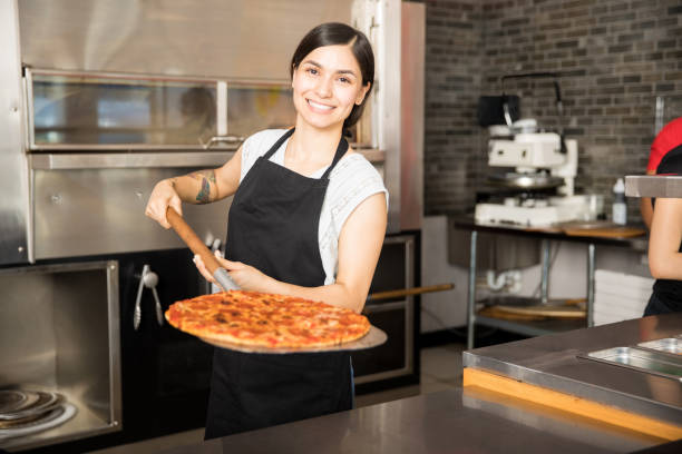 istock Smiling chef holding big peel with pizza 1000842142