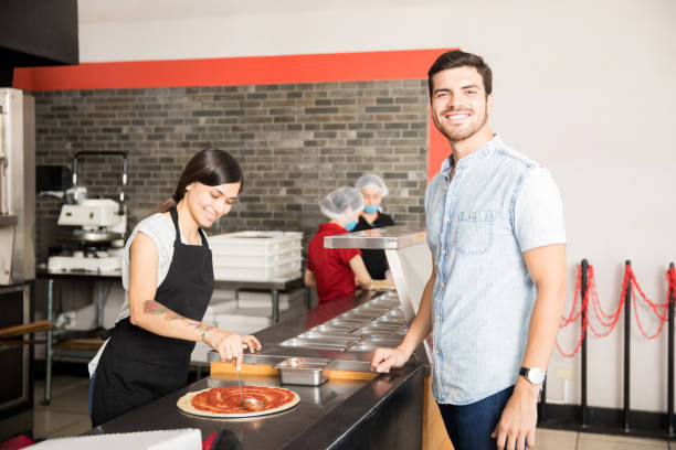 istock Smiling woman chef smearing tomato ketchup over pizza 1000842810