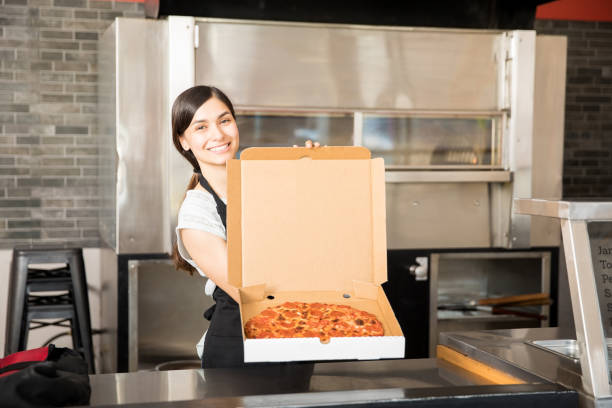 young smiling chef with pizza in open box - pizzeria imagens e fotografias de stock