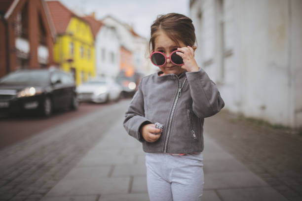 Lovely and beautiful child standing on a street in fashionable jacket.