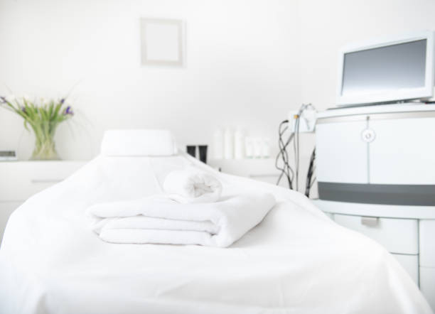 Digital device locating opposite coach Light cozy bed with fluffy towels situating near special gadget with modern screen. Design concept beauty clinic stock pictures, royalty-free photos & images