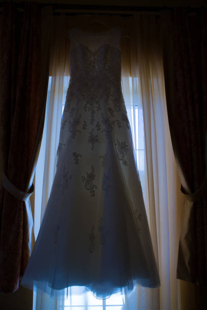 istock wedding dress hanging on window at hotel room. 1000849766