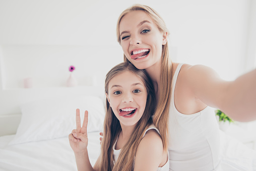 Indoors domestic lifestyle grimace fooling concept. Close up portrait of cute cool funky funny beautiful pretty excited rejoicing delightful mom and offspring making taking self picture in bed room