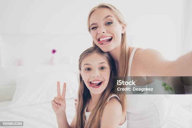 Indoors Domestic Lifestyle Grimace Fooling Concept Close Up Portrait Of Cute Cool Funky Funny Beautiful Pretty Excited Rejoicing Delightful Mom And Offspring Making Taking Self Picture In Bed Room Stock Photo - Download Image Now
