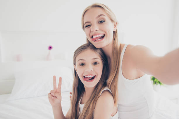 indoors domestic lifestyle grimace fooling concept. close up portrait of cute cool funky funny beautiful pretty excited rejoicing delightful mom and offspring making taking self picture in bed room - kid photo imagens e fotografias de stock