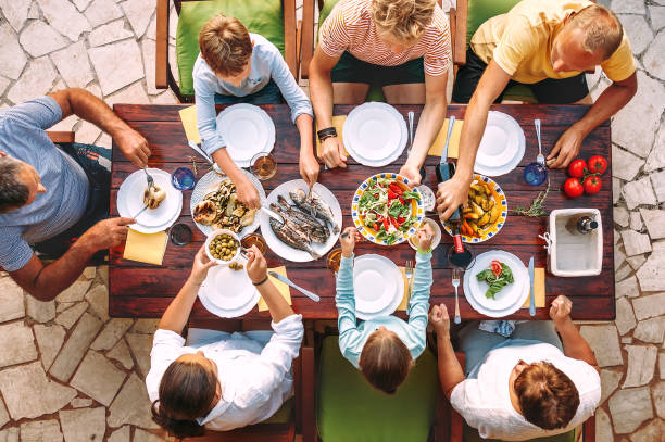 grande famille avoir un dîner avec des repas cuisinés frais sur la terrasse du jardin ouvert - wine food fish seafood photos et images de collection