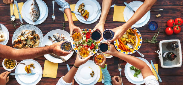 Big family dinner. Vertical top view on served table and hands with clinking goblets