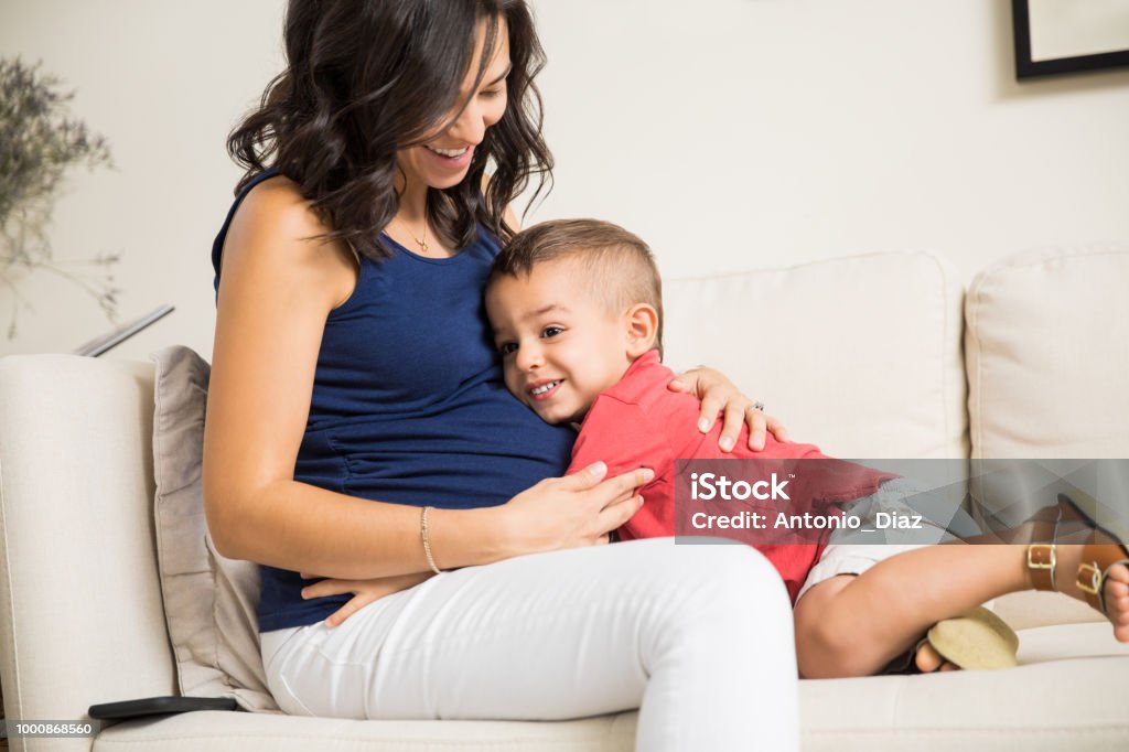 Boy Showing Love Towards Unborn Baby In Mother's Tummy Cute little boy showing love towards unborn baby in mother's tummy at home Pregnant Stock Photo