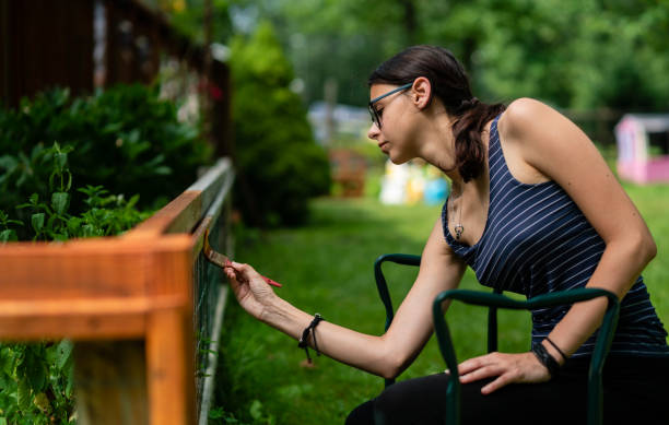 裏庭のフェンスを塗る魅力的な 15 歳のティーンエイ ジャーの女の子 - 13 14 years 写真 ストックフォトと画像