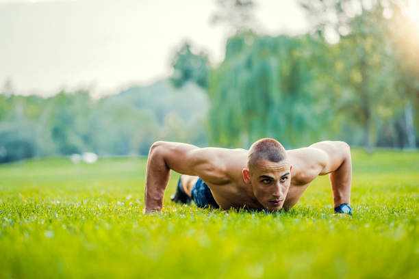 istock Dedicated man exercising on grassy field on sunny day 1000877886