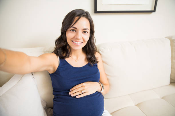 Woman Capturing Pregnancy Moments While Sitting On Sofa