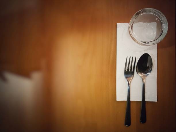 istock Table setting with a retro vintage low key light theme. fork and spoon, napkin, tissue, glass with copy space for label text, top view. 1000895994