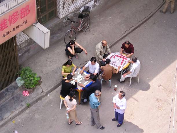 The Mahjong Players of Xian 19th August 2003.  Xian, China.  Local people enjoy a warm summer's afternoon chatting and playing mahjong or looking on. They stand or sit at tables put out in the street, to take advantage of any occasional breeze that may occur. mcdermp stock pictures, royalty-free photos & images