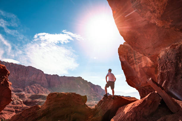 Hiker looking at mountain view from a large rock formation in Utah, in panoramic view