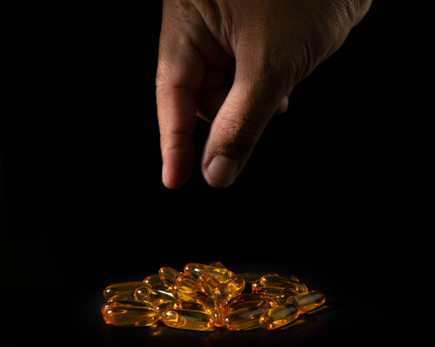 fish oil capsules and finger - vitamin pill picking up pill capsule imagens e fotografias de stock