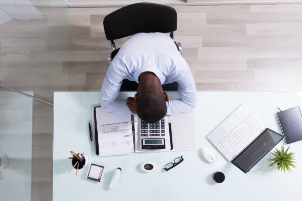 istock Overhead View Of A Businessman Sleeping At Workplace 1000962392