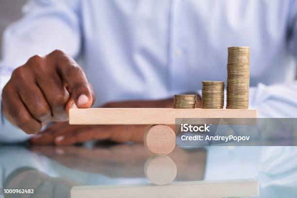 Businessman Balancing The Coin Stack On Wooden Seesaw Stock Photo - Download Image Now