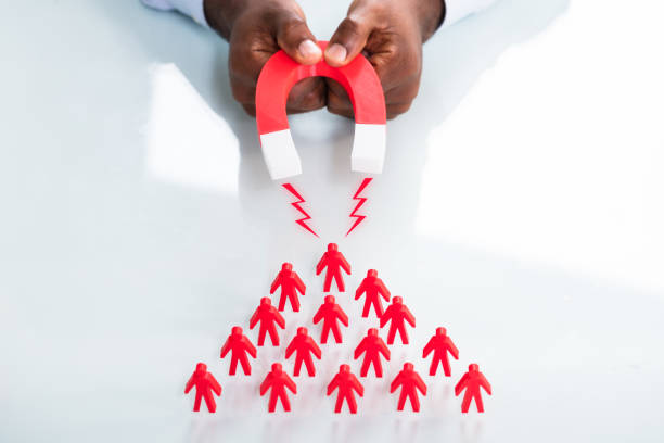 istock Human Hand Attracting Red Human Figures With Horseshoe Magnet 1000962500