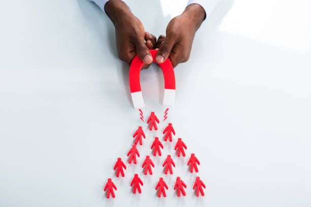 istock Human Hand Attracting Red Human Figures With Horseshoe Magnet 1000962518