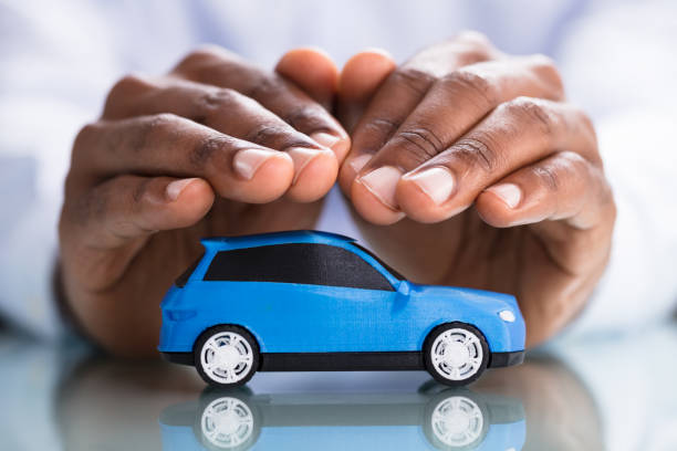 istock Businessman's Hand Protecting Blue Toy Car 1000962528