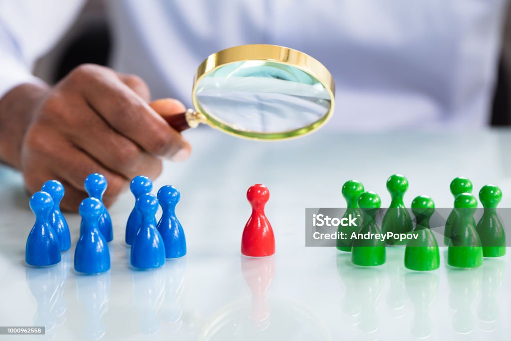 Male Looking At Colorful Pawns With Magnifying Glass A Male Looking At Colorful Pawns With Magnifying Glass On The Reflective Desk Midsection Stock Photo