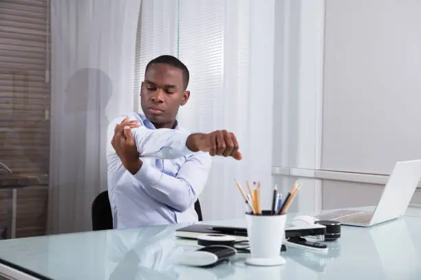 Close-up Of Businessman Stretching Her Hands At Workplace