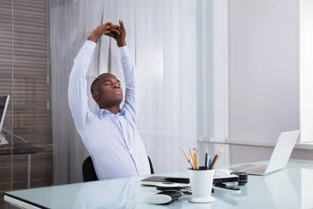 Close-up Of Businessman Stretching Her Hands At Workplace