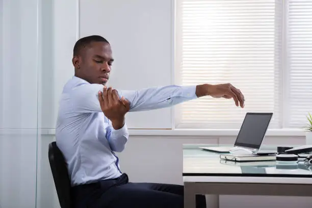 Close-up Of Businessman Stretching Her Hands At Workplace