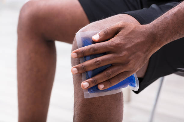 Man Applying Ice Gel Pack On His Knee Close-up Of A Man Applying Ice Gel Pack On His Knee ice pack photos stock pictures, royalty-free photos & images