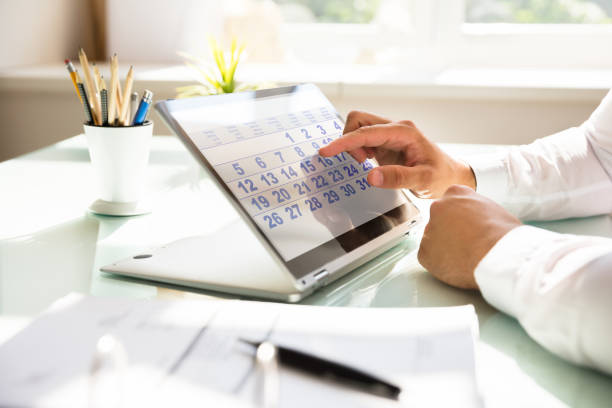 Businessman using calendar on laptop Close-up of a businessman's hand using calendar on laptop over desk calendar deadline stock pictures, royalty-free photos & images