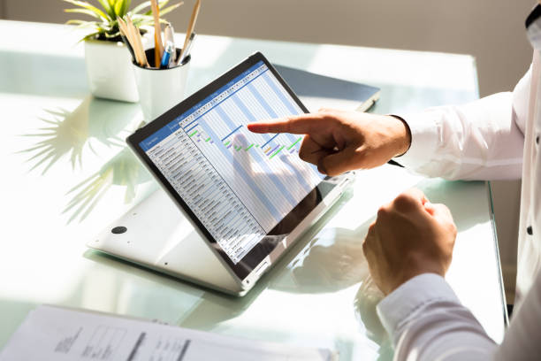 Businessman analyzing gantt chart on laptop Businessman's hand analyzing gantt chart on laptop over reflective desk control point stock pictures, royalty-free photos & images