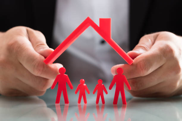 istock Person protecting family figures with roof 1000964630