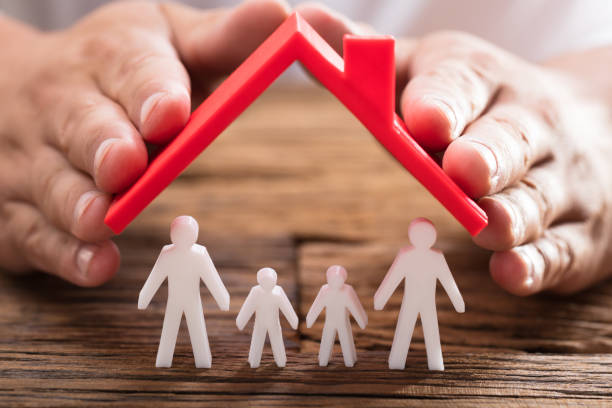 Person protecting family figures with roof