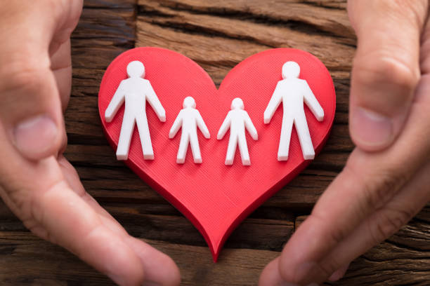 istock Person protecting red heart with family figures 1000964664