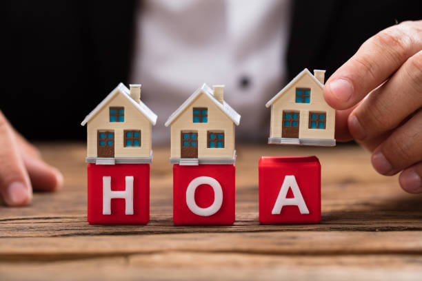 Businessperson placing house model over HOA blocks Businessperson's hand placing house model over red HOA blocks on wooden desk rood stock pictures, royalty-free photos & images