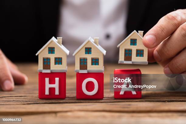 Businessperson Placing House Model Over Hoa Blocks Stock Photo - Download Image Now - Home Ownership, Organized Group, Community