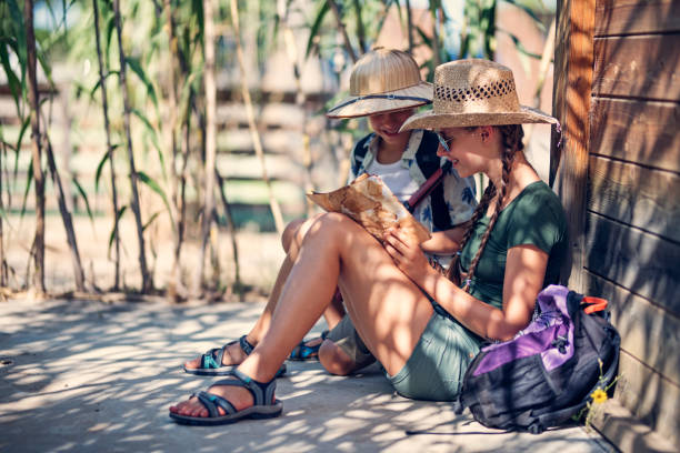Kids playing safari exploration trip. Brother and sister sitting near wood cabin and reading an ancient treasure map.Sunny summer day.Nikon D850