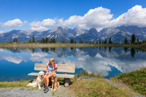 カイザー山で彼女の犬と一緒に銀行に座っている女性 - lake mountain north tirol austria ストックフォトと画像