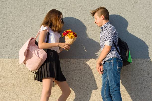 Boy gives girl bouquet of flowers. Outdoor portrait of couple teenagers. Boy gives girl bouquet of flowers. Outdoor portrait of couple teenagers teen romance stock pictures, royalty-free photos & images
