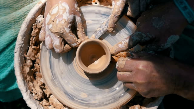 Top view on Potter's Hands Work with Clay on a Potter's Wheel. Slow motion