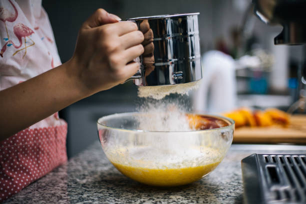 istock Young woman sifting flour into bowl at the kitchen 1001002542