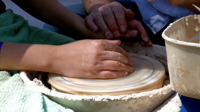 Potter's hands work with clay on a potter's wheel