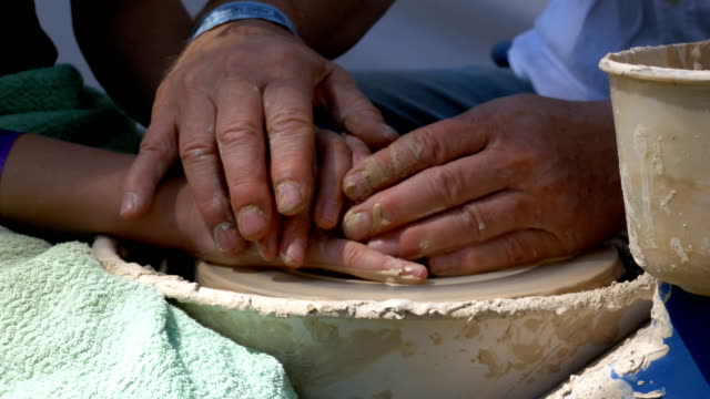 Hands of the master potter and vase of clay on the potter's wheel close-up